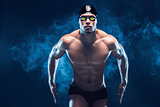 Attractive and muscular swimmer. Studio shot of young shirtless sportsman on black background. Man with glasses