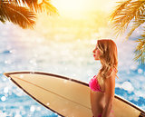 Beautiful young female with surfboard in bikini in a tropical beach