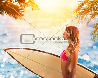 Beautiful young female with surfboard in bikini in a tropical beach