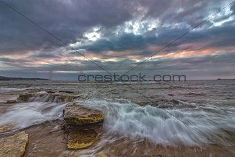 long exposure seascape with slow shutter and waves flowing out at sunset