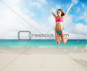 Woman in bikini swimsuit jumping from joy on tropical beach