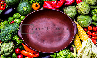 Cooking background concept. Fresh organic vegetables around empty clay pot
