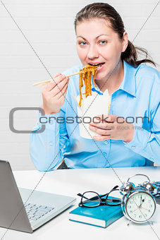 Hungry girl eating noodles at the office