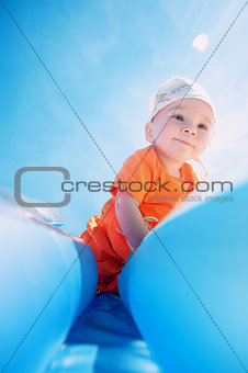 A small child with an inflatable mattress on the beach on a hot summer day. Smiling boy playing on the beach with an air mattress Summer Vacations