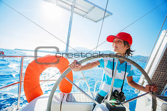 Little boy captain on board of sailing yacht on summer cruise. Travel adventure, yachting with child on family vacation.
