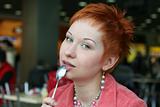 red haired woman wih spoon is smiling in cafe