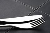 metal fork and knife with abstract light on black leather place 