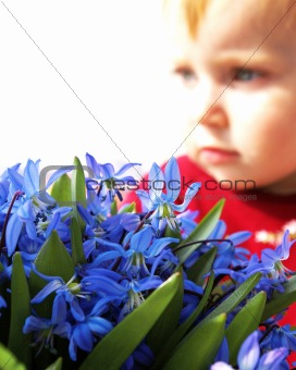 Little girl looks at a bouquet of snowdrops