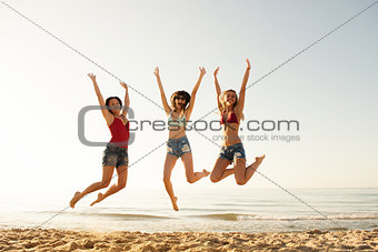 Happy smiling friends jumping at the beach