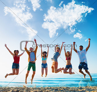 Happy smiling friends jumping over a blue sky with a world map made of clouds