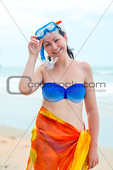 Happy girl in bikini near the sea on the beach in a mask for div