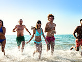 Group of friends run in the sea. Concept of summertime
