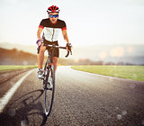 Cyclist racing on the road at sunset
