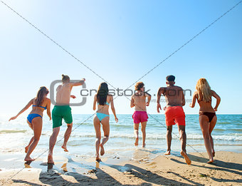 Group of friends run to the sea. Concept of summertime