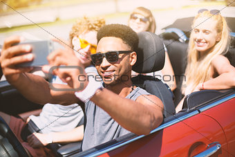 Young friends take a selfie in a cabriolet car