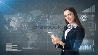 Beautiful woman in suit looking into a touch pad, painted studio background with copyspace. Business concept.