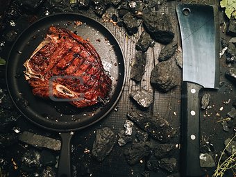 A large roasted steak lies on a dark frying pan.