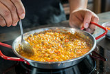 Chef is cooking paella with spoon, close up
