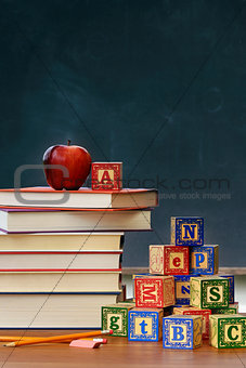 Stack of books with apple and wooden blocks