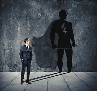 Businessman with his shadow of super hero on the wall. Concept of powerful man