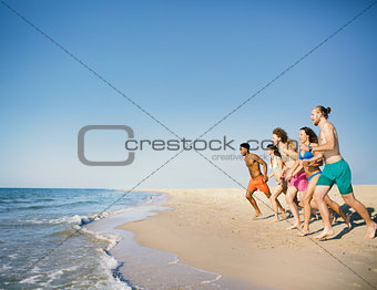 Group of friends run to the sea. Concept of summertime