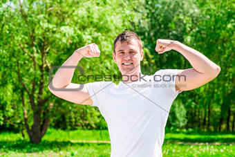 Strong and handsome man posing in summer park