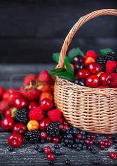 Berries mix in basket on dark wooden background