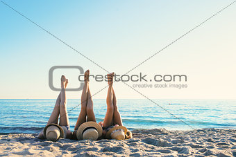 Group of happy friends having fun at ocean beach with legs up