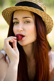 Sexy woman in hat eating strawberry in garden.