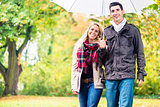 Couple enjoying fall day having walk despite the rain