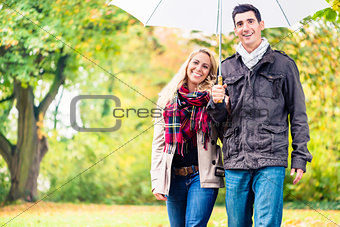 Couple enjoying fall day having walk despite the rain