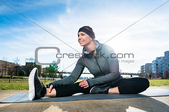 Young beautiful woman smiling while sitting down in a stretching