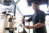 Serious bartender pouring fresh milk into a cup of coffee in a t