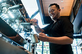 Young cheerful barista preparing coffee at an automatic machine