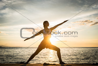 Silhouette of a fit woman practicing the warrior yoga pose again