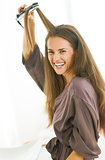 smiling young woman straightening hair with straightener