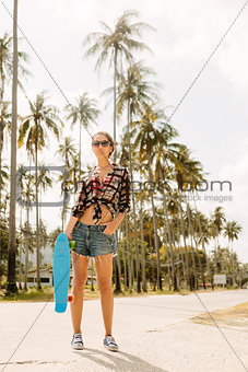 Pretty girl with skateboard on the road.