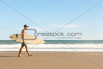 Handsome man with surfing board on spot.