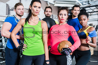 Group of women and men in gym posing at fitness training