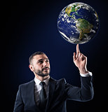 Businessman holds the world with a finger. World provided by NASA
