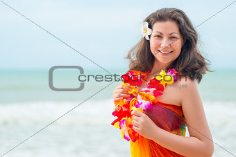 Happy young brunette in pareo and flower lei against the sea