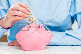 Close-up of a pink piggy bank and a hundred dollar money stock