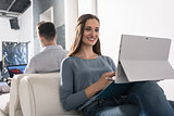 Woman sitting in armchair with smartphone and laptop PC