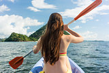 Young woman paddling a canoe on the sea during summer vacation i