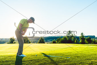 Experienced male golfer hitting the golf ball towards the cup du