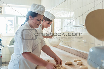 Women in bakery forming raw dough to pretzels