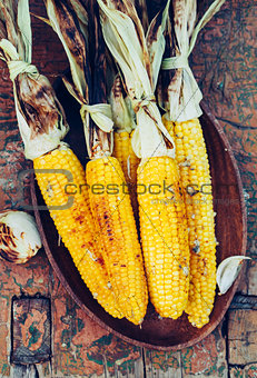 Grilled corn cobs on old wooden table.
