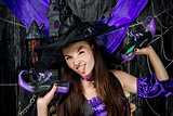 horizontal portrait of a cheerful witch with shoes in hands on a