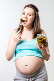 Hungry pregnant woman with a jar of pickled cucumbers against a 