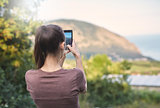 young woman photographing the landscape by smartphone camera